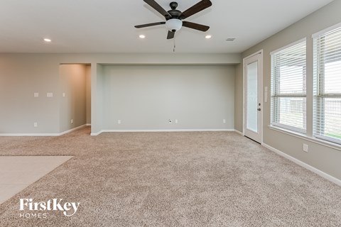 A spacious room with a carpeted floor and a ceiling fan.