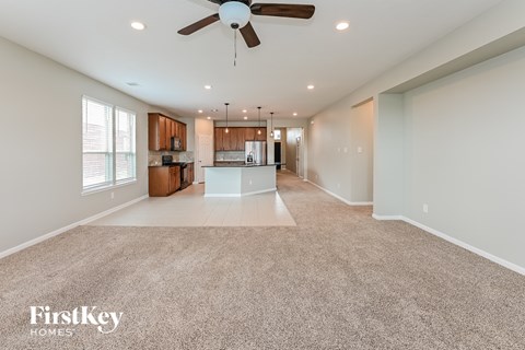 A spacious living room with a fan and a carpeted floor.