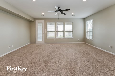 A spacious room with a carpeted floor and a ceiling fan.
