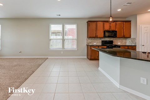 A kitchen with a black stove top oven and wooden cabinets.