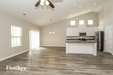 an open kitchen and living room with white cabinets and stainless steel appliances