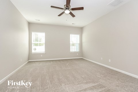 the spacious living room with ceiling fan and carpet