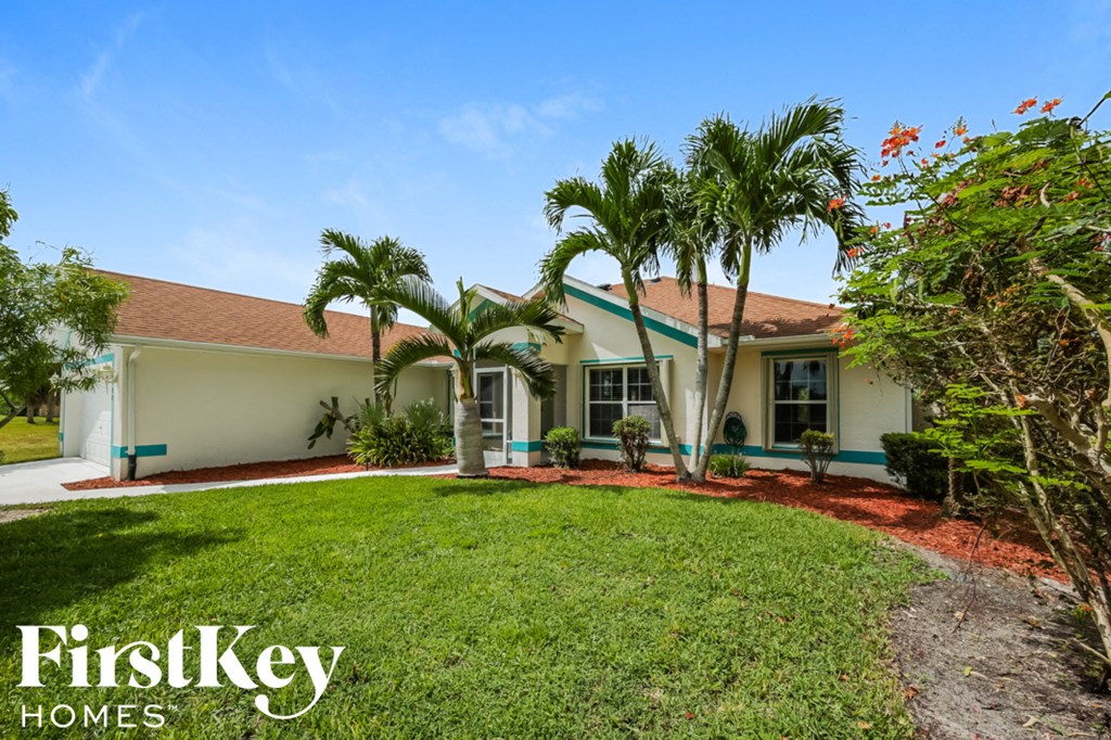 A white house with a red roof and a green lawn in front.