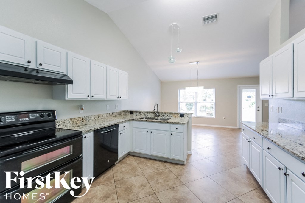 A kitchen with white cabinets and a black stove top oven.