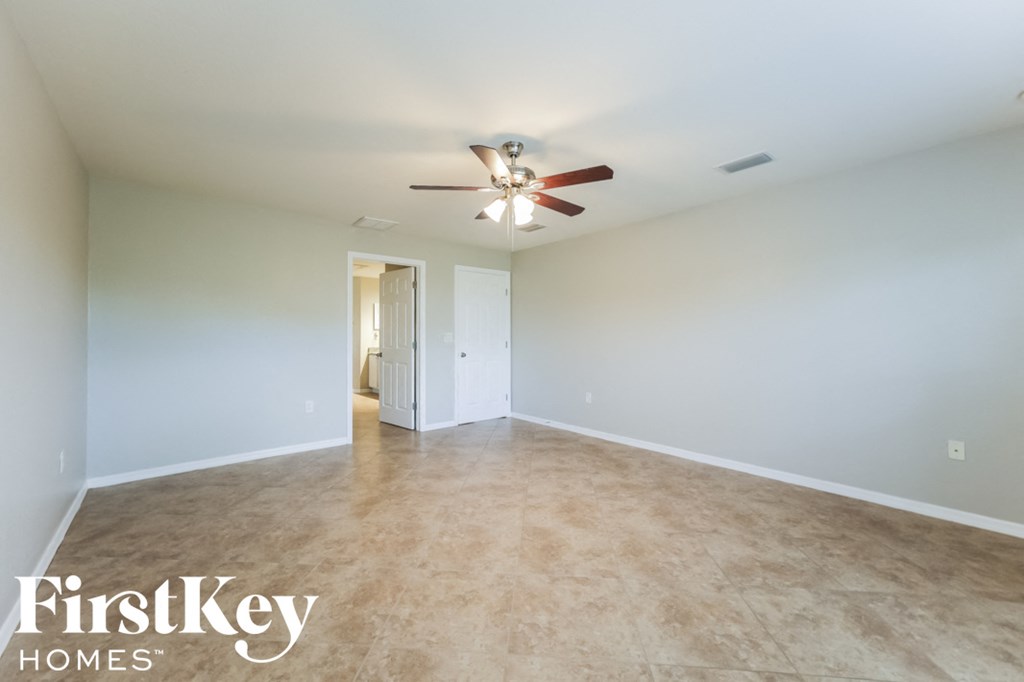 A spacious room with a ceiling fan and a door leading to another room.
