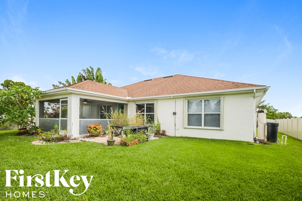 A white house with a brown roof and a green lawn in front.