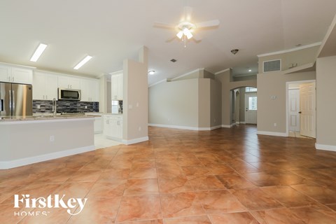 an open kitchen and living room with tile flooring and a ceiling fan