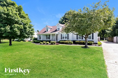 a white house with a lawn and trees in front of it