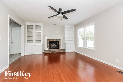 an empty living room with a fireplace and a ceiling fan