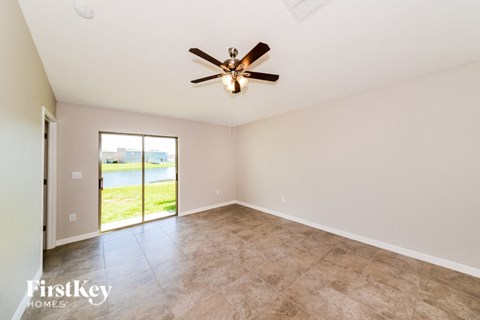 A room with a ceiling fan and sliding glass doors leading to a lawn.
