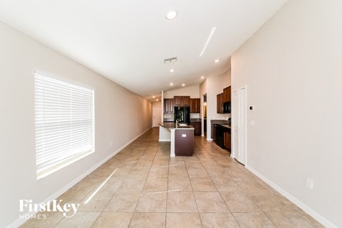 A spacious room with a kitchen in the background and a refrigerator in the foreground.