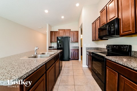 A kitchen with brown cabinets and black appliances.