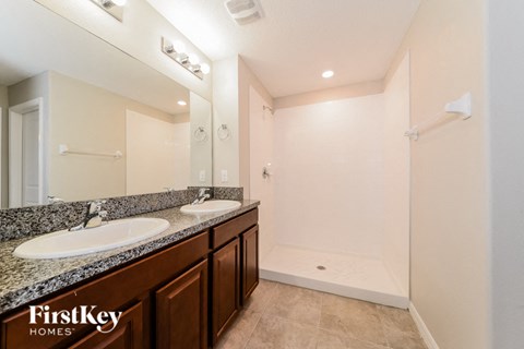 A bathroom with a double sink vanity and a walk-in shower.