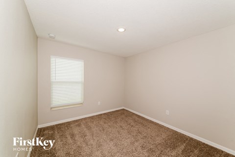 A room with a carpeted floor and a window with blinds.