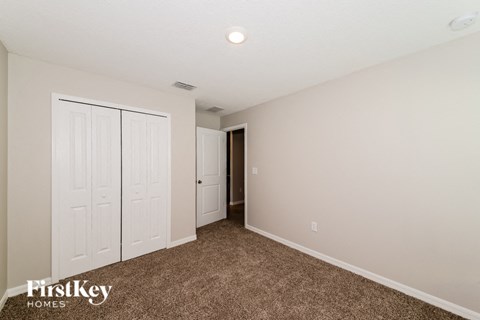 A carpeted room with a white door and a wall with a switch.
