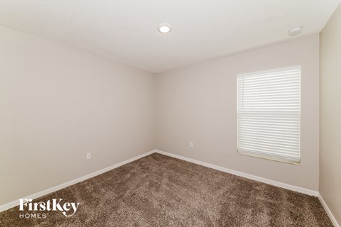 A room with a carpeted floor and a window with blinds.