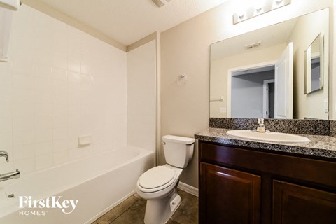 A bathroom with a toilet, sink, and mirror.