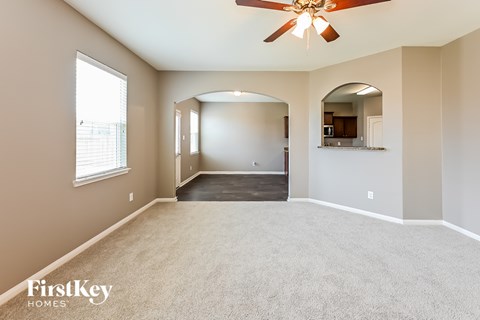A spacious room with a ceiling fan and a large mirror on the wall.