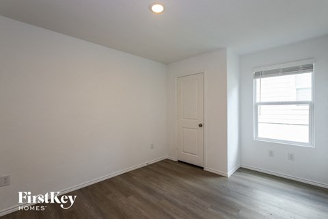 a bedroom with white walls and wood floors and a white door