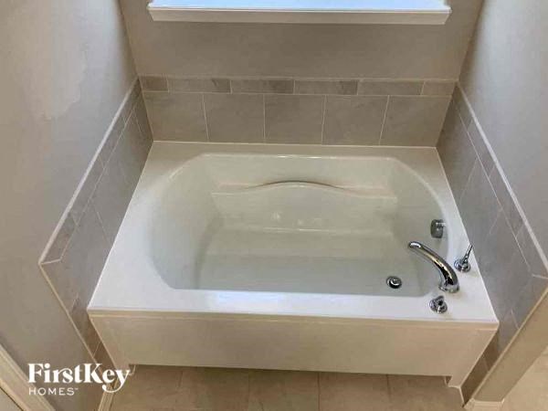 a white bath tub in a bathroom with a window