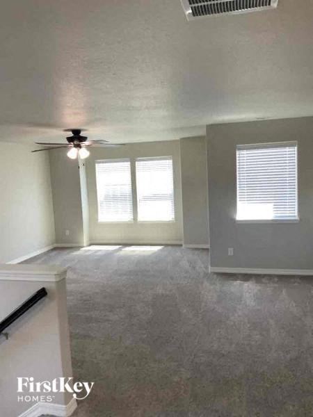 an empty living room with a ceiling fan