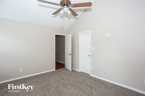 a bedroom with a ceiling fan and a door to a closet