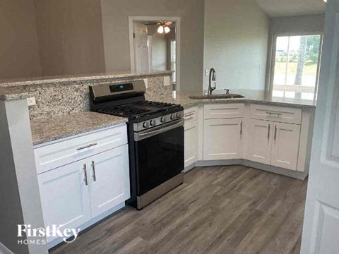 A kitchen with a black stove top oven and white cabinets.