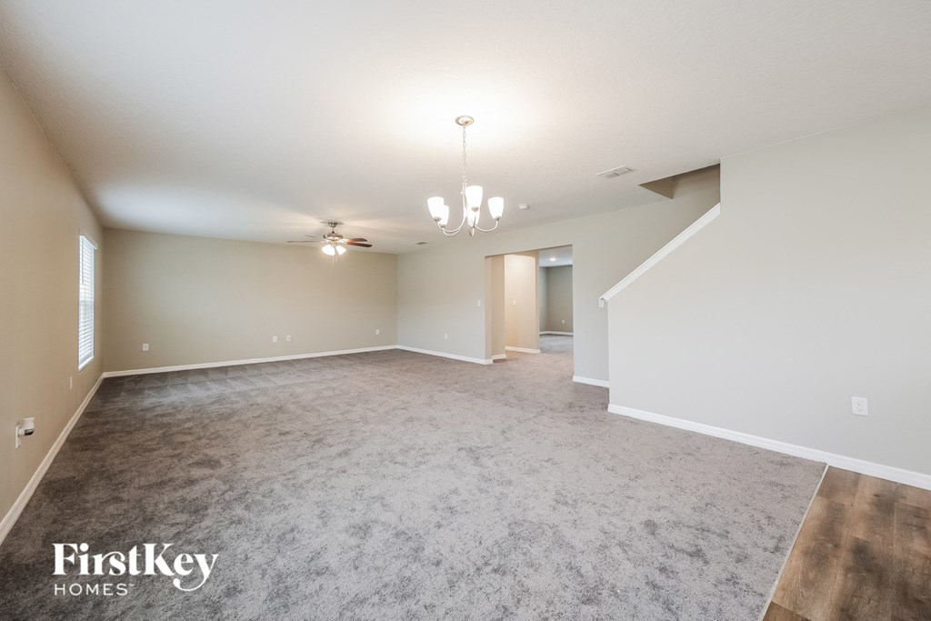 a spacious living room with carpet and a ceiling fan