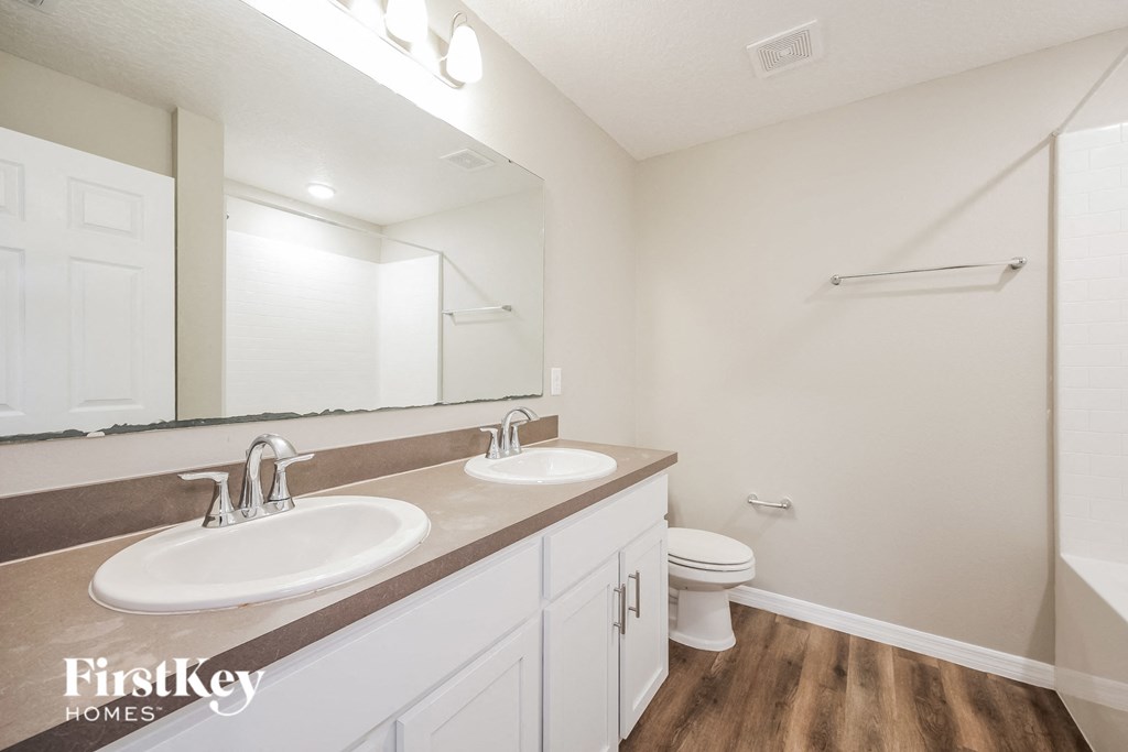 a bathroom with two sinks and a toilet and a mirror
