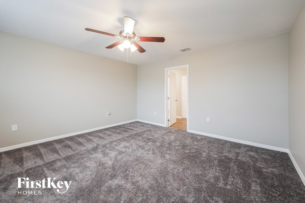 a spacious living room with carpet and a ceiling fan