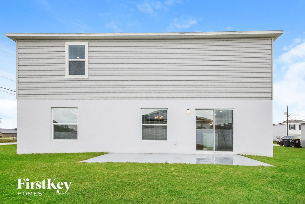 the exterior of a white house with three windows and a lawn