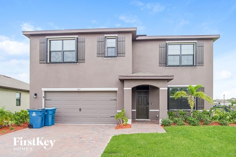 a beige house with a garage door and a lawn
