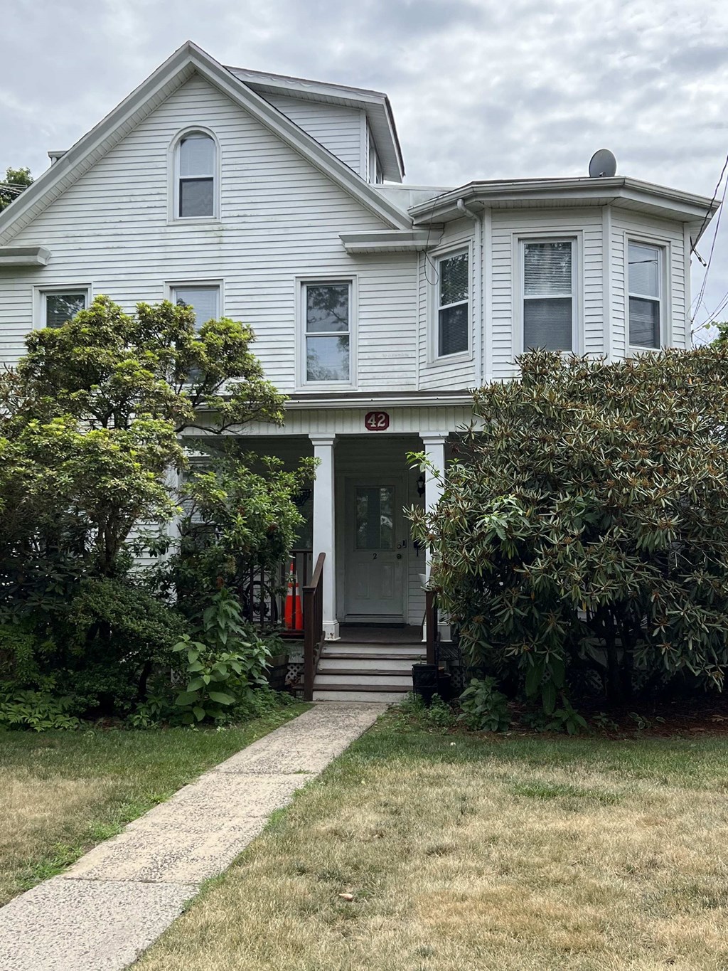 the front of a white house with a lawn and a sidewalk