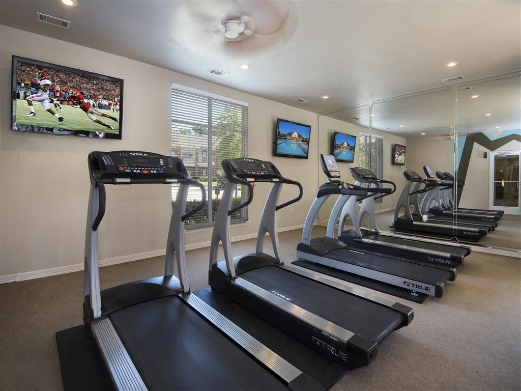 a gym with several treadmills and a tv