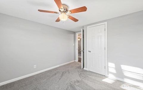 a bedroom with a ceiling fan and a door to a bathroom