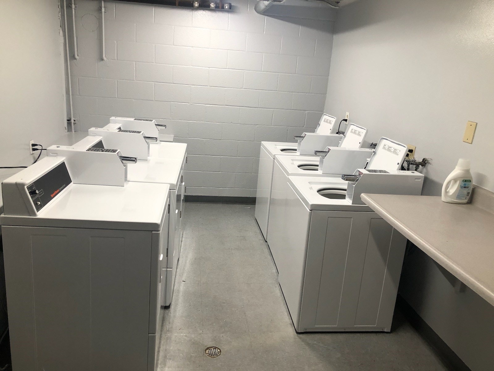 A row of washing machines are lined up in a laundry room.