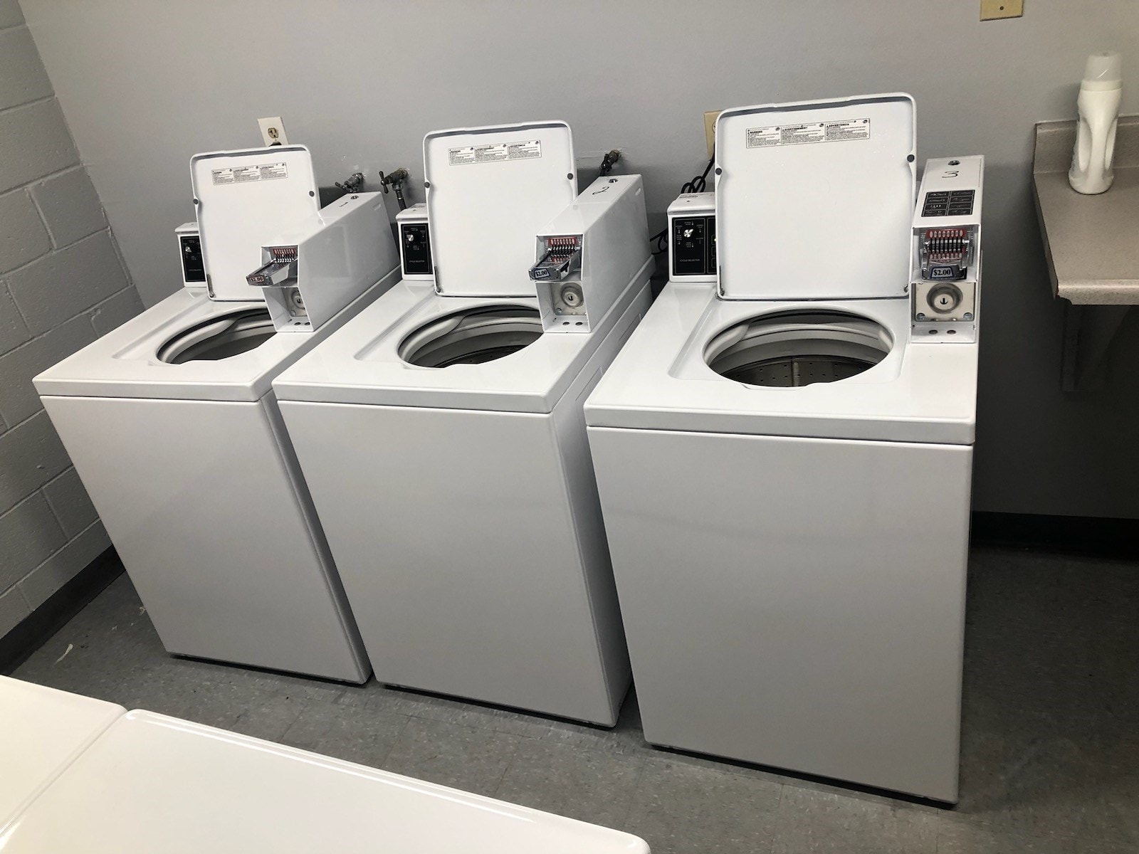 Three white toilets are lined up in a row.