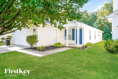a small white house with a lawn and a porch