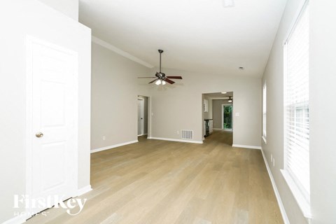 an empty living room with a ceiling fan and wood floors
