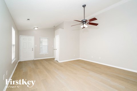 a living room with white walls and a ceiling fan