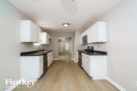 an empty kitchen with white cabinets and black counter tops