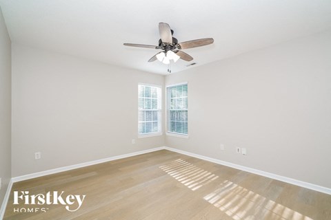 an empty living room with a ceiling fan and a window
