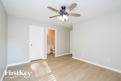 a living room with a ceiling fan and a door to a bedroom