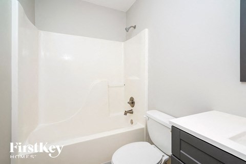 a white bathroom with a toilet and a tub