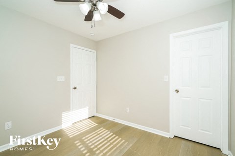 a empty room with a ceiling fan and two doors
