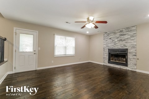 an empty living room with a fireplace and a ceiling fan