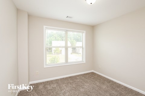a bedroom with a large window and a carpeted floor