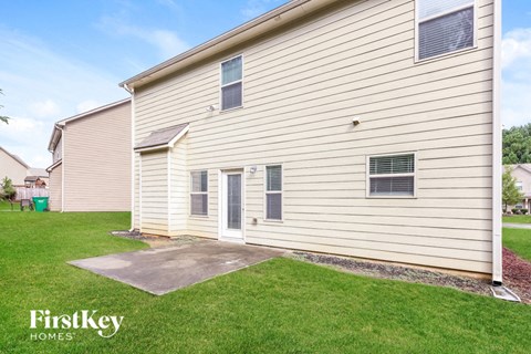 a side view of the side of a house with a driveway and grass
