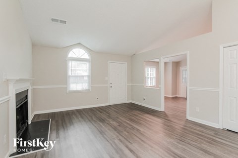 an empty living room with a fireplace and wood flooring