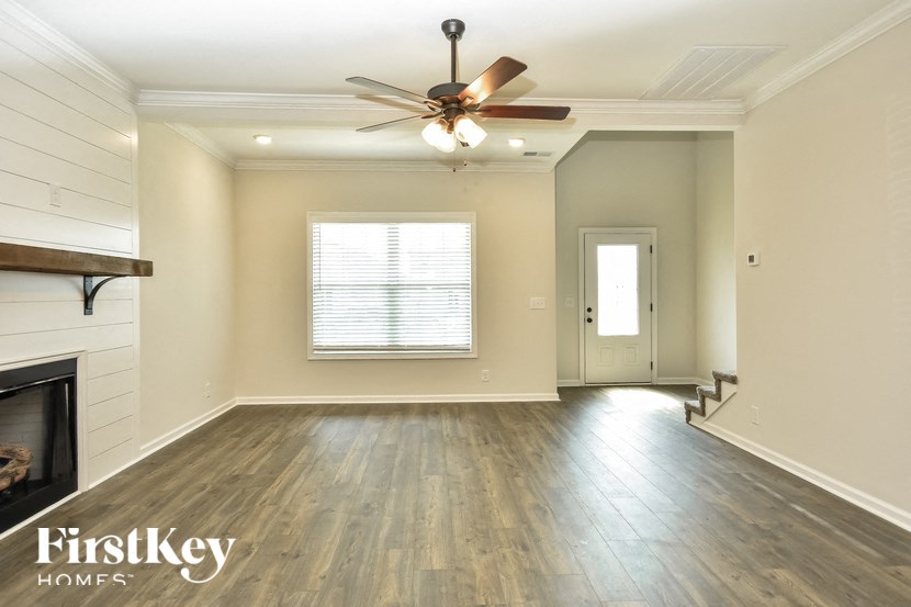 an empty living room with wood floors and a ceiling fan